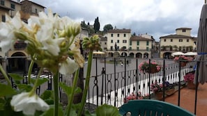A courtyard with a fountain, surrounded by buildings with balconies and flower pots. - Typical  apartment in the central square of Greve with a panoramic terrace + A/C (Greve in Chianti)