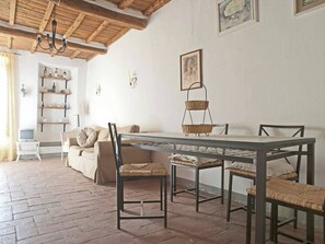 Un comedor con una mesa y sillas de madera, un sofá y un televisor al fondo.