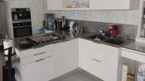 A modern kitchen with white cabinets, a stainless steel sink, and a built-in oven.