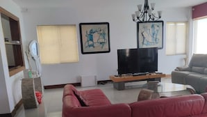 A living room with a red sofa, a flat-screen TV, and artwork on the wall.