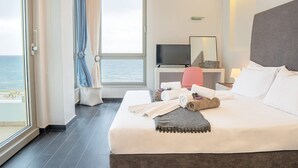 Ein Hotelzimmer mit Bett, Fernseher, Schreibtisch und Meerblick.