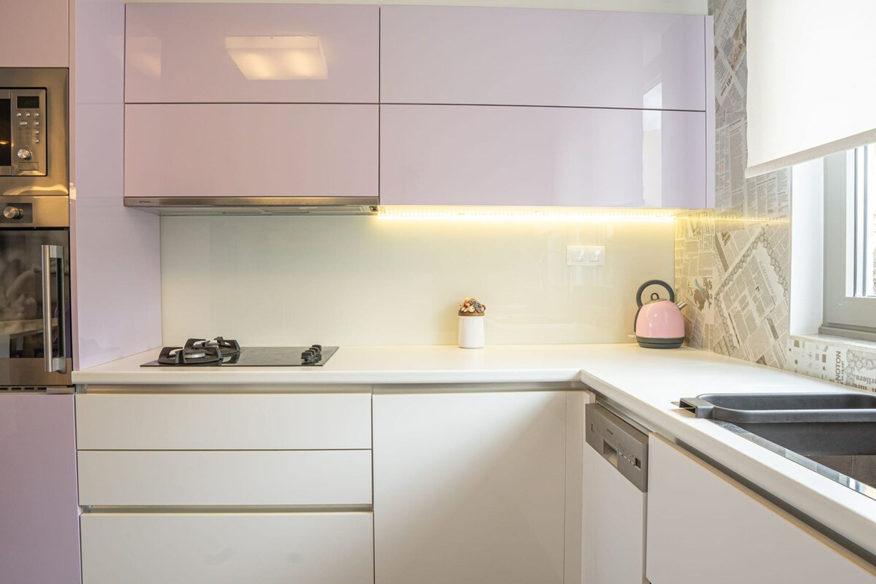 Una cocina moderna con armarios blancos, horno integrado y campana extractora de acero inoxidable.