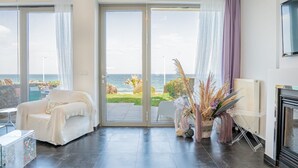 Ein modernes Wohnzimmer mit einer großen Schiebetür zu einem Balkon mit Meerblick.