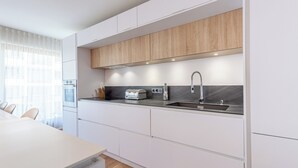 A modern kitchen with white cabinets, a black countertop, and a stainless steel sink. - La Quinta - Appartement en Centre ville (Annecy)