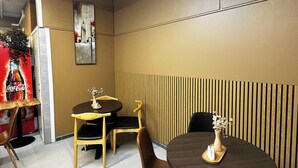 A dining area with two round tables, chairs, and a decorative wall panel. - Eidsdal Hotel & Restaurant As (Eidsdal)