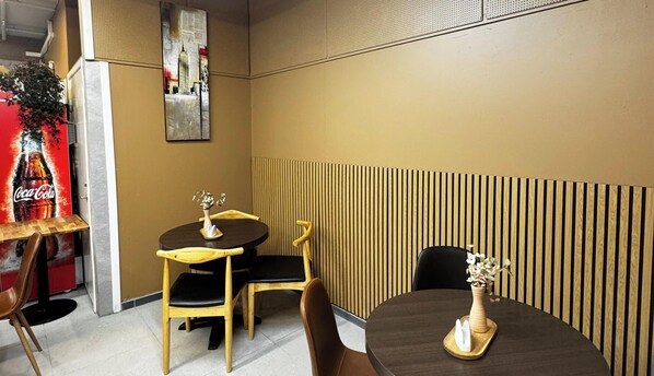 A dining area with two round tables, chairs, and a decorative wall panel. - Eidsdal Hotel & Restaurant As (Eidsdal)