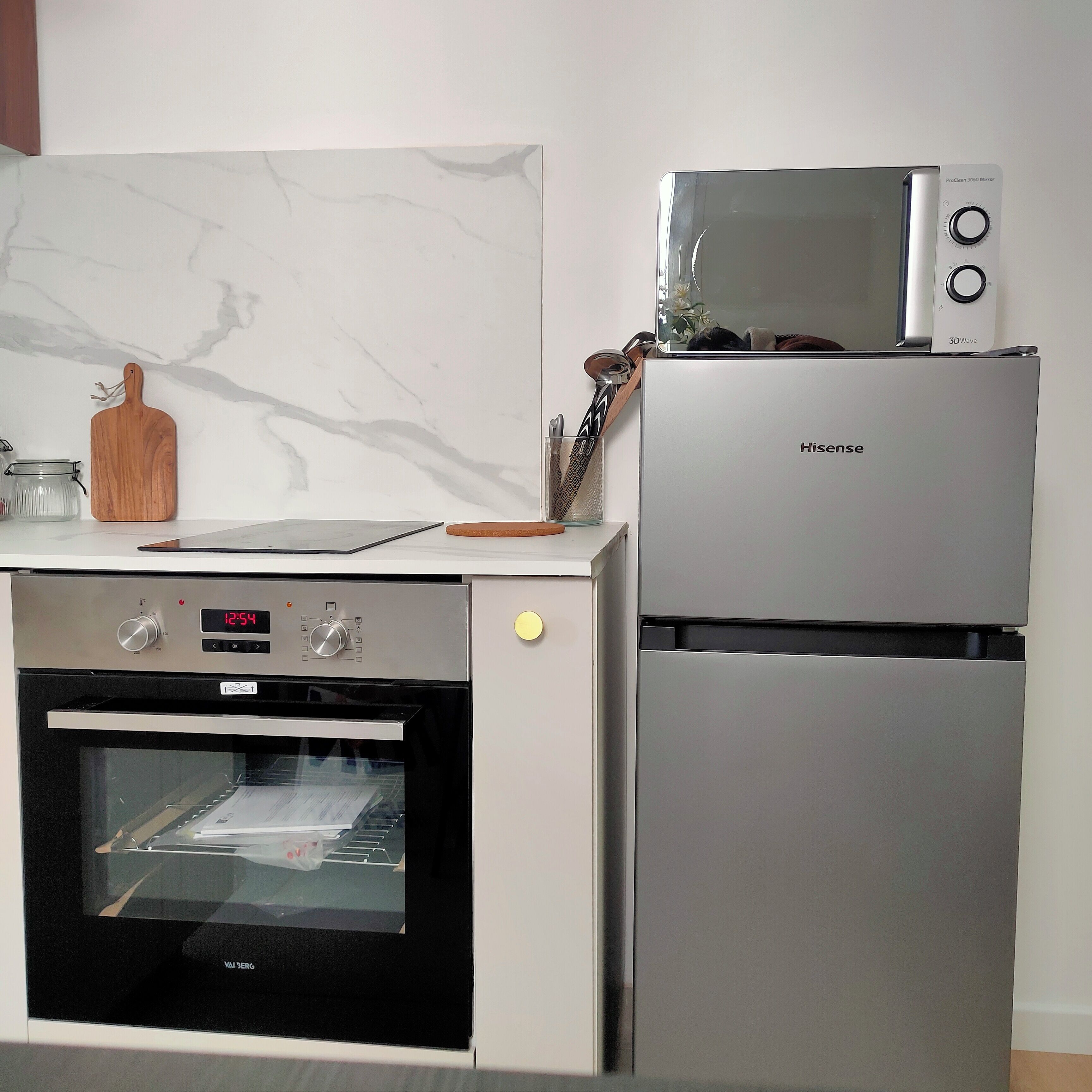 Una cucina compatta con forno a incasso, microonde e frigorifero.