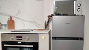 Une cuisine compacte équipée d’un four encastré, d’un four à micro-ondes et d’un réfrigérateur.