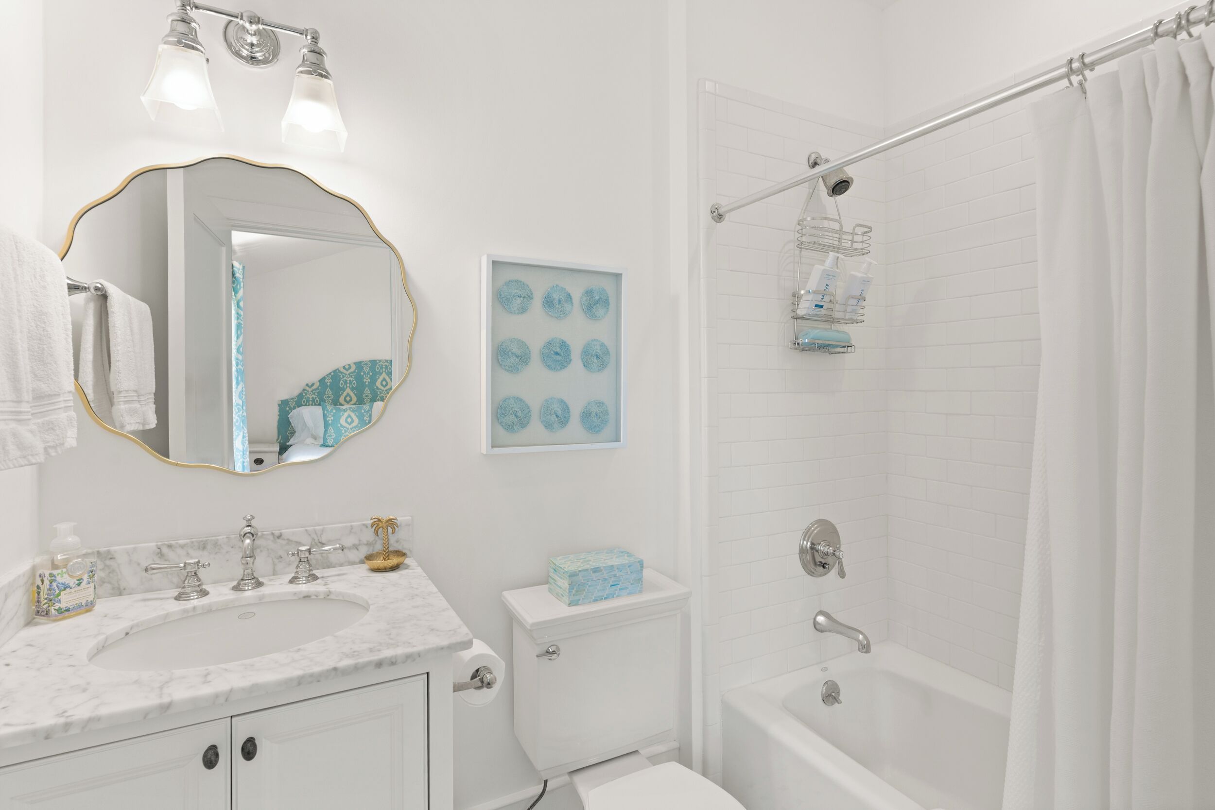Un baño con lavamanos blanco, espejo, inodoro y bañera.