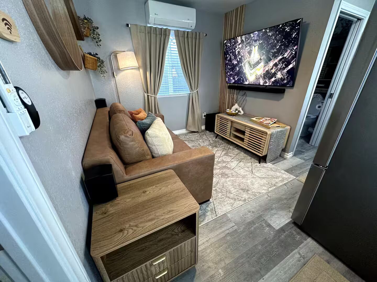 Una sala de estar moderna con sofá, televisor y una pequeña mesita de madera.