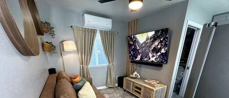 A living room with a brown sofa, a TV, a wooden console, and a ceiling fan.