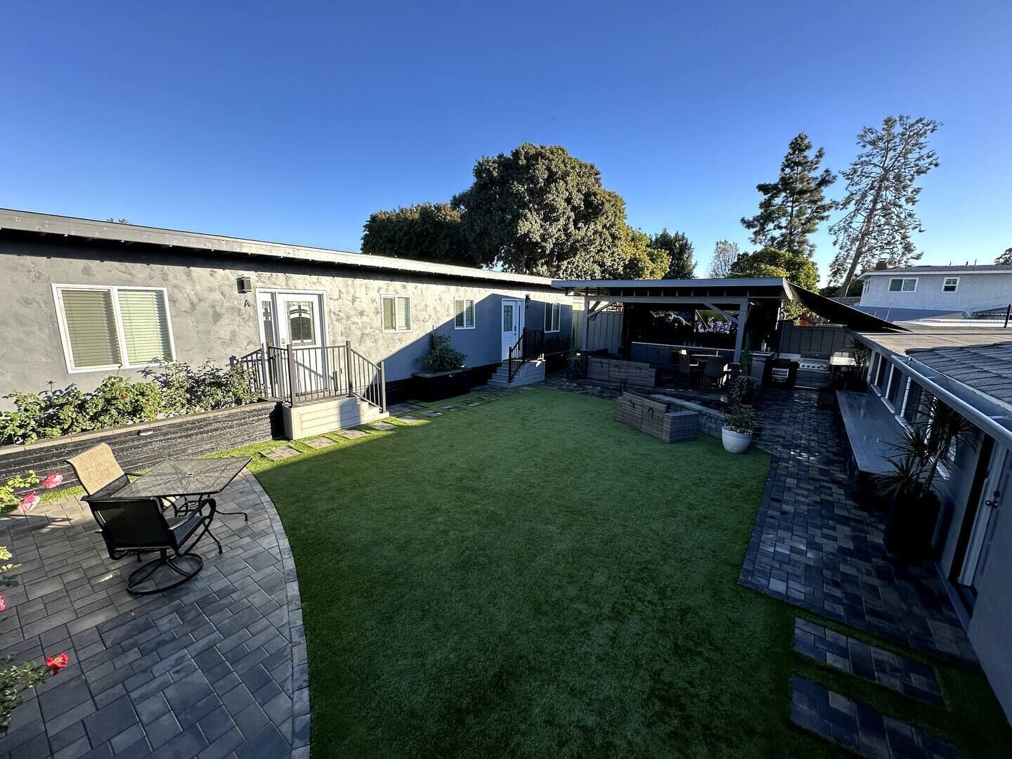 A residential backyard with a patio, a covered outdoor seating area, and a small lawn.