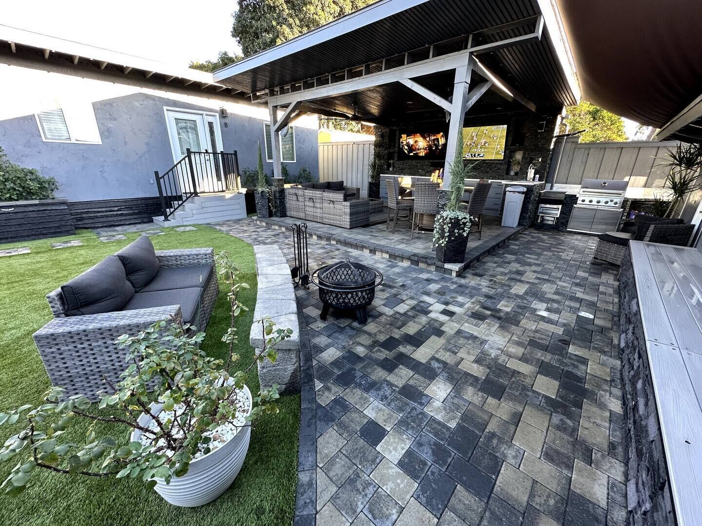 Ein Patio mit überdachter Sitzgelegenheit, Grill und einem Blumentopf.