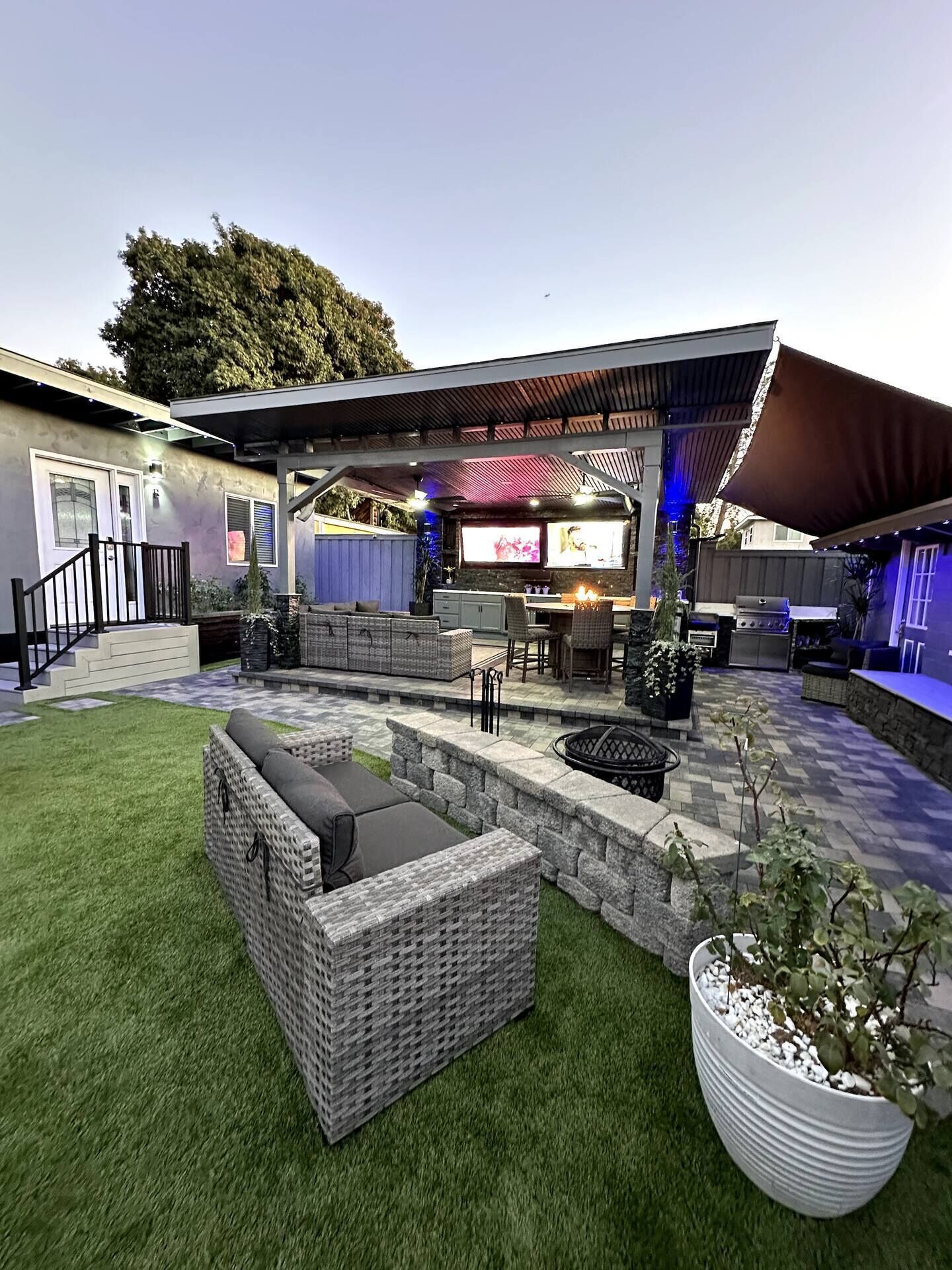 Une terrasse extérieure couverte, équipée d’un barbecue, d’un coin salon et d’un écran de télévision.
