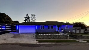A residential house with a garage, a driveway, and a small front yard with a stone planter.