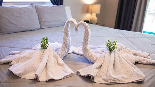 A bed with two towels shaped like swans and a small plant on each. - Coastal Coral Paradise with Heated Pool (Cape Coral)