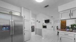 A modern kitchen with white cabinetry, a stainless steel refrigerator, and a tiled backsplash. - Diamond Waters near DFW & Stadium with Private Pool (Fort Worth)