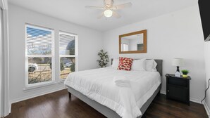A bedroom with a bed, a nightstand, a mirror, and a ceiling fan. - Diamond Waters near DFW & Stadium with Private Pool (Fort Worth)
