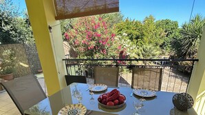 Zona de menjador exterior coberta amb taula ben posada per a dues persones, envoltada de cadires i vistes a un jardí ple de plantes i arbres.