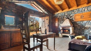 A rustic cabin interior with a stone fireplace, wooden furniture, and a dining area. - House Finca Relax Cercadillo (Santa Ursula)