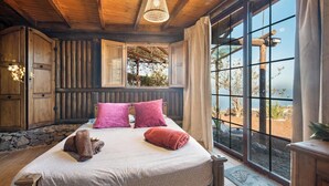 A cozy bedroom with a large bed, wooden walls, and a view of the outdoors. - House Finca Relax Cercadillo (Santa Ursula)