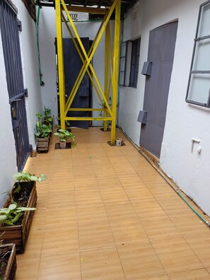 A narrow corridor with wooden flooring, yellow structural beams, and potted plants. - Wrech House 1989 - Sagana (Sagana)