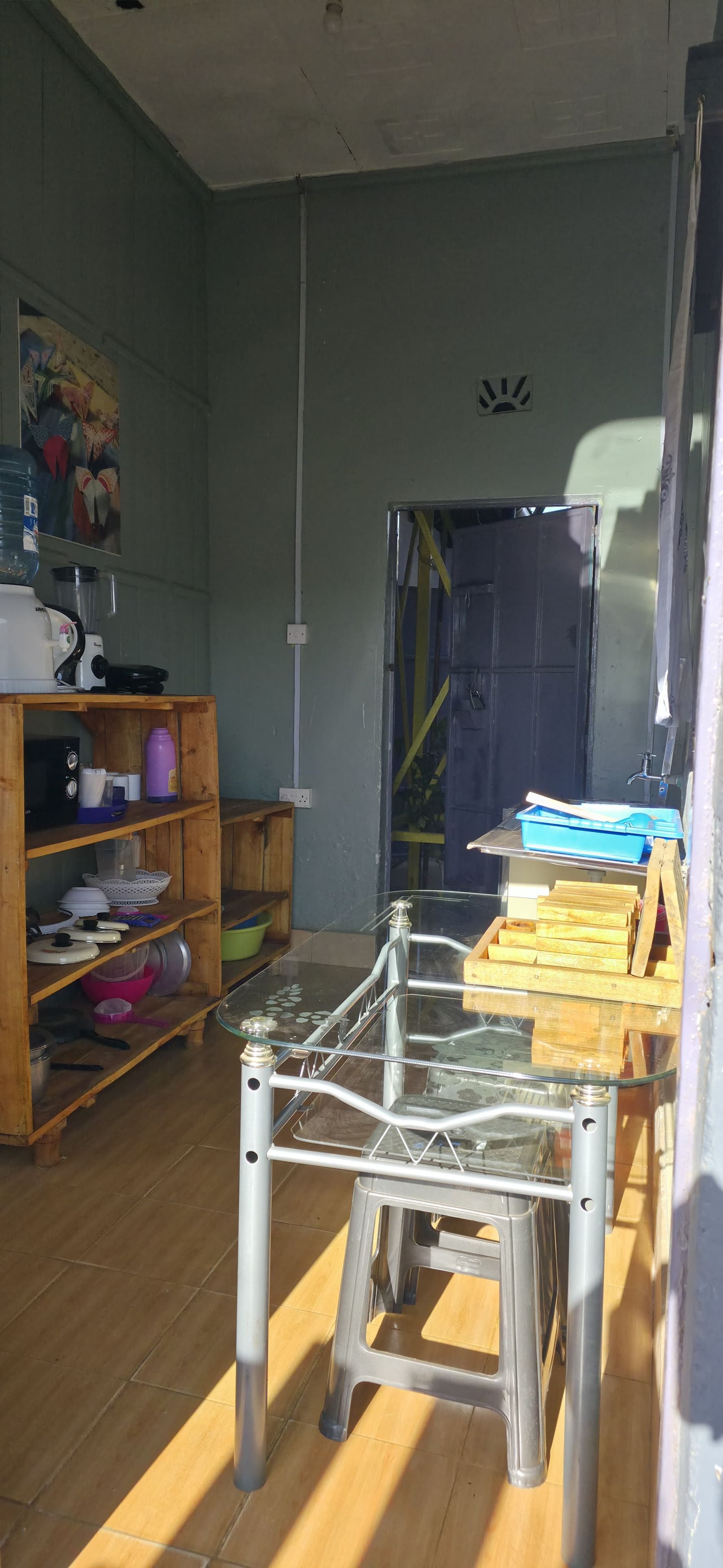A room with a metal-framed table, wooden shelves, and a blue door.