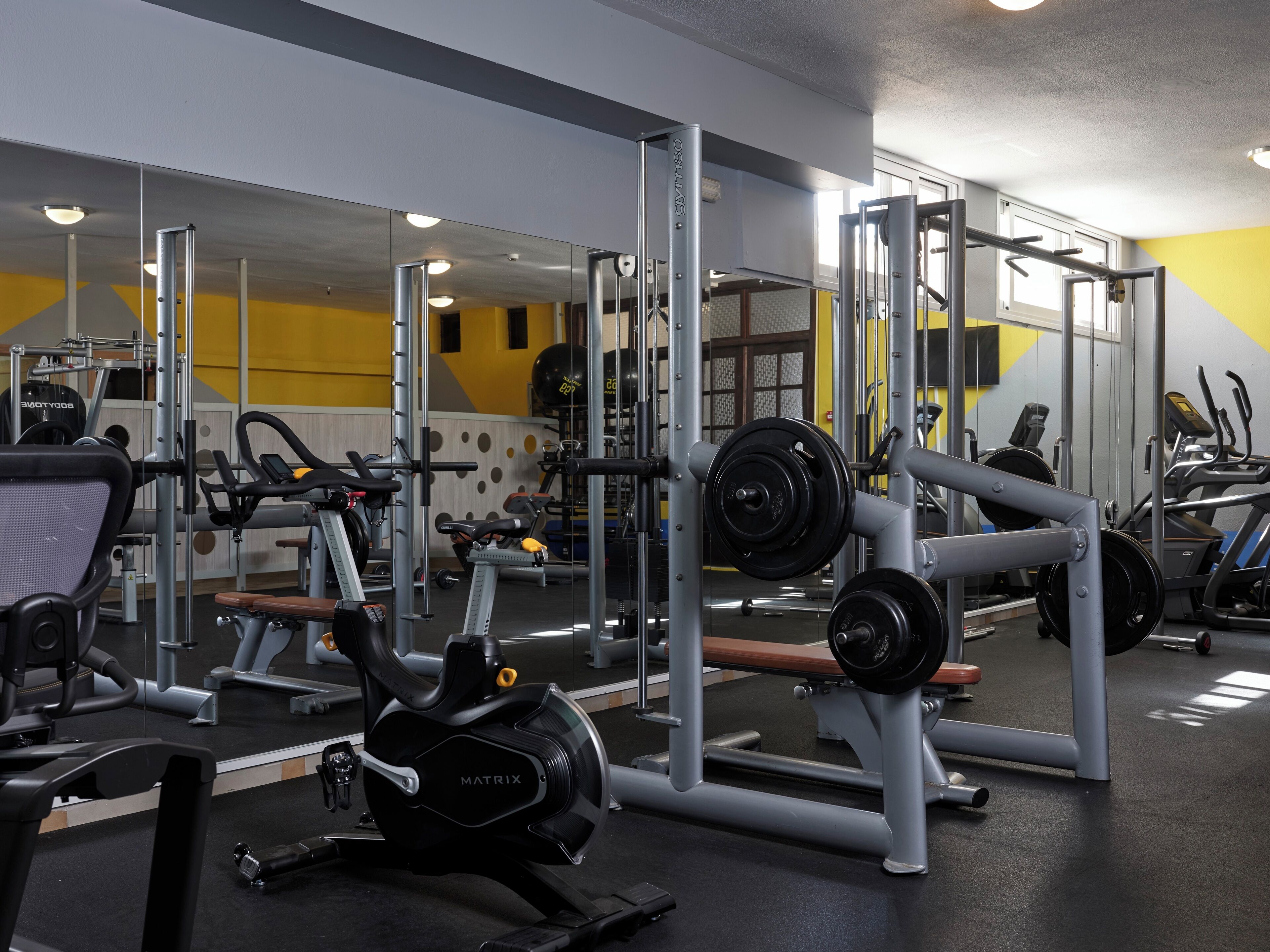 Un gimnasio con diversos equipos de ejercicio, incluyendo cintas de correr, máquinas de pesas y una bicicleta estática.