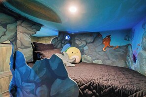 Una habitación con una cama, un mural en la pared y una ventana.