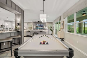 Un espacio moderno para vivir con mesa de billar, cocina y comedor.