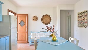 A dining area with a blue table, white chairs, and a vase with flowers. - Villa Menhir! (Sardegna)