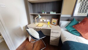A compact bedroom with a desk, chair, and bed.