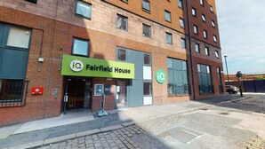 A building with a green sign reading "iQ Fairfield House" and a circular logo with "iQ" on the side.