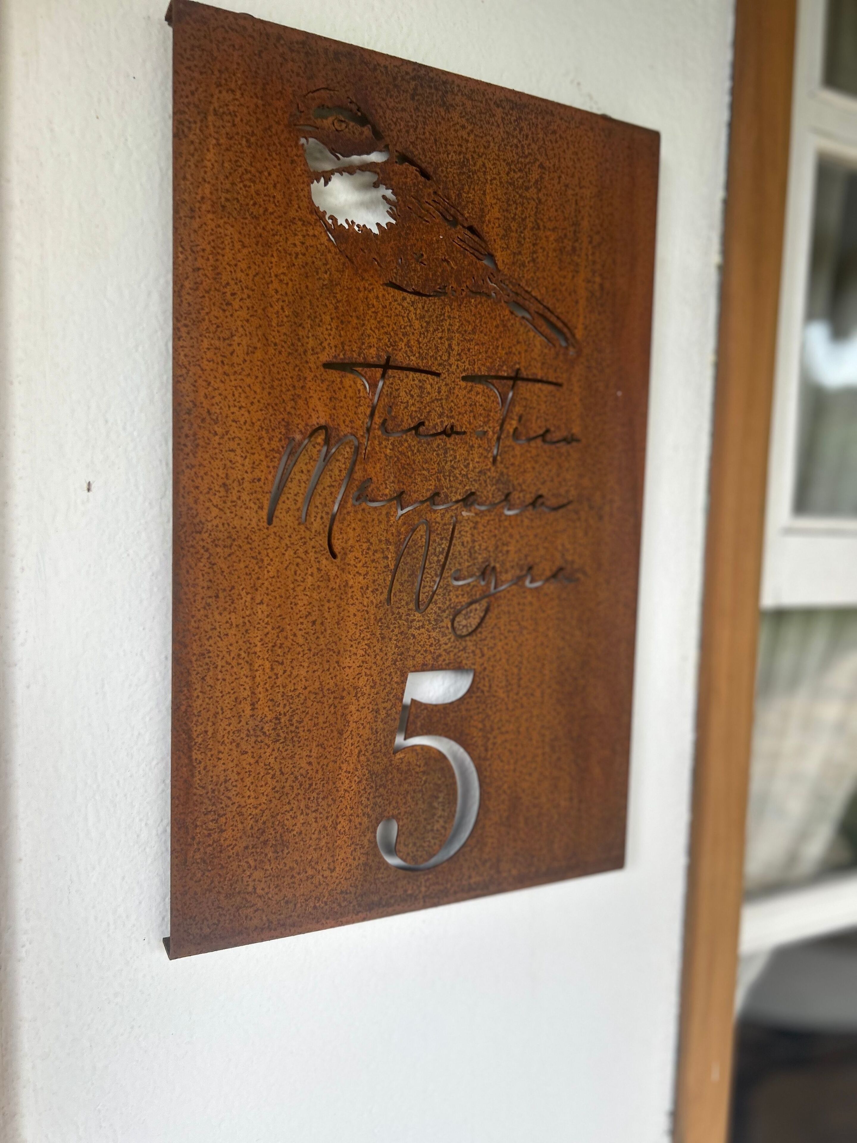 A metal plaque with a bird, handwritten text, and the number 5.