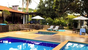Un espace piscine aménagé avec des chaises longues, des parasols et un mur en pierre.