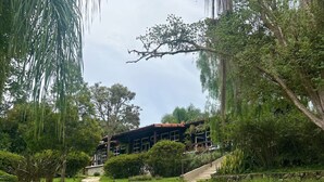 Un chemin de pierre mène à un bâtiment entouré d’une végétation luxuriante et d’arbres.