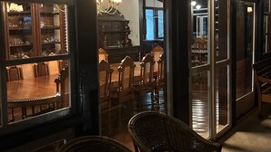 Une pièce spacieuse avec une grande table à manger et des chaises en osier, un plancher en bois et un lustre.