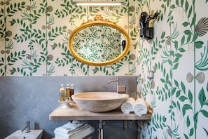 A bathroom with a large oval mirror, a stone sink, and a towel rack.