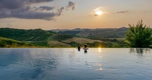 Una piscina infinita con vistas a colinas ondulantes y una puesta de sol.