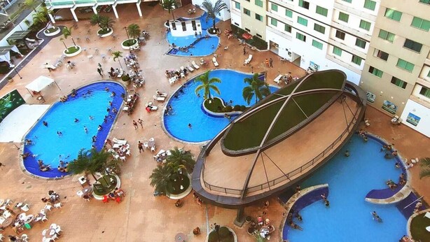 A hotel with multiple swimming pools, outdoor seating areas, and a covered walkway. - Hotel Riviera Caldas Novas, in the city center. Pet friendly, (Turista 1 Caldas Novas)