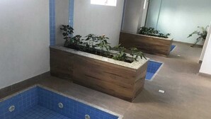 A hotel bathroom with a blue-tiled shower area, wooden planter boxes with plants, and a tiled floor. - Hotel Riviera Caldas Novas, in the city center. Pet friendly, (Turista 1 Caldas Novas)