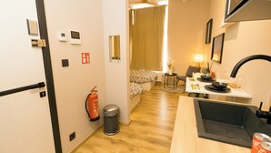 Una cuina compacta amb un rentapeus, una zona de menjador amb taula i cadires, i un petit espai de estar amb un sofà.