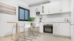 Een moderne keuken met witte kastjes, een ingebouwde oven en een raam.