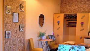 Een gezellige kamer met een houten wand, een ronde spiegel, een tafeltje met een plant, een gele stoel en een bloemenbank.