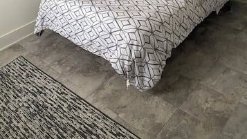 A single bed with a geometric patterned bedspread and matching pillows, a small rug, and two wall-mounted artworks depicting nautical themes.