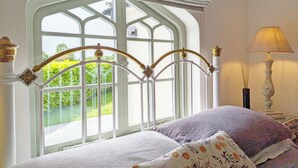 Una camera da letto con un'ampia finestra, un letto con lenzuola a motivi floreali e una lampada da comodino.