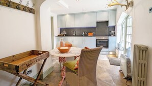 Una cucina moderna con un'isola centrale, un'area pranzo con sedie in vimini e un'ampia finestra che offre luce naturale.