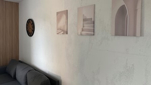 A living room with a gray sofa, a wooden panel wall, and three framed artworks depicting abstract designs. - Modern apartment - top location (Witten)