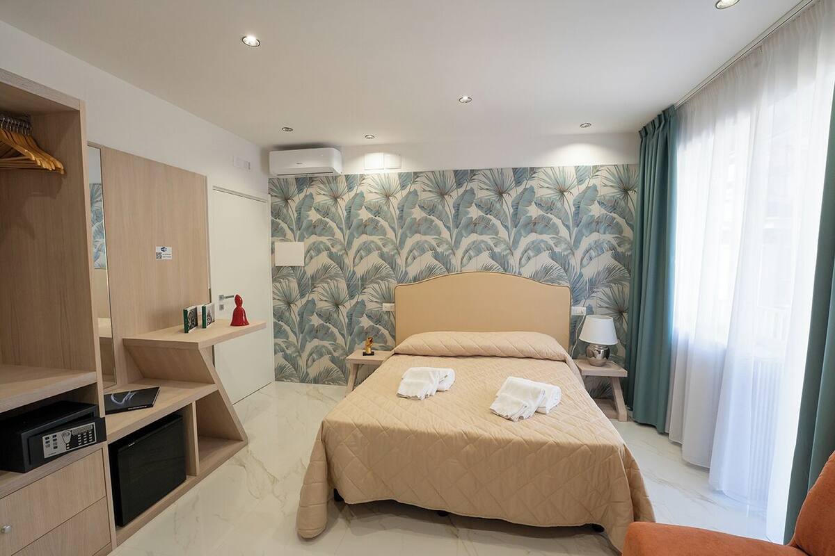 A hotel room with a bed, a bedside table with a lamp, a wardrobe, and a television.