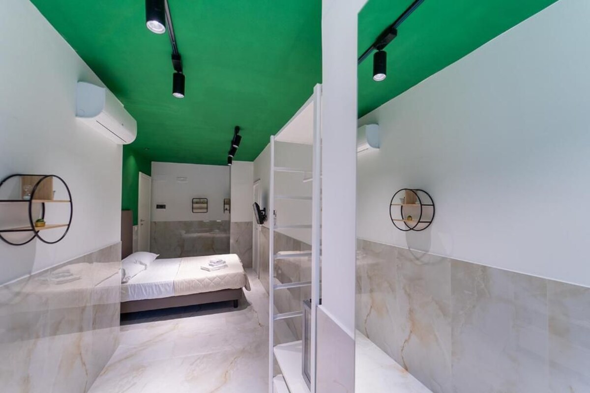 A modern bedroom with a bed, a walk-in closet, and a green ceiling.